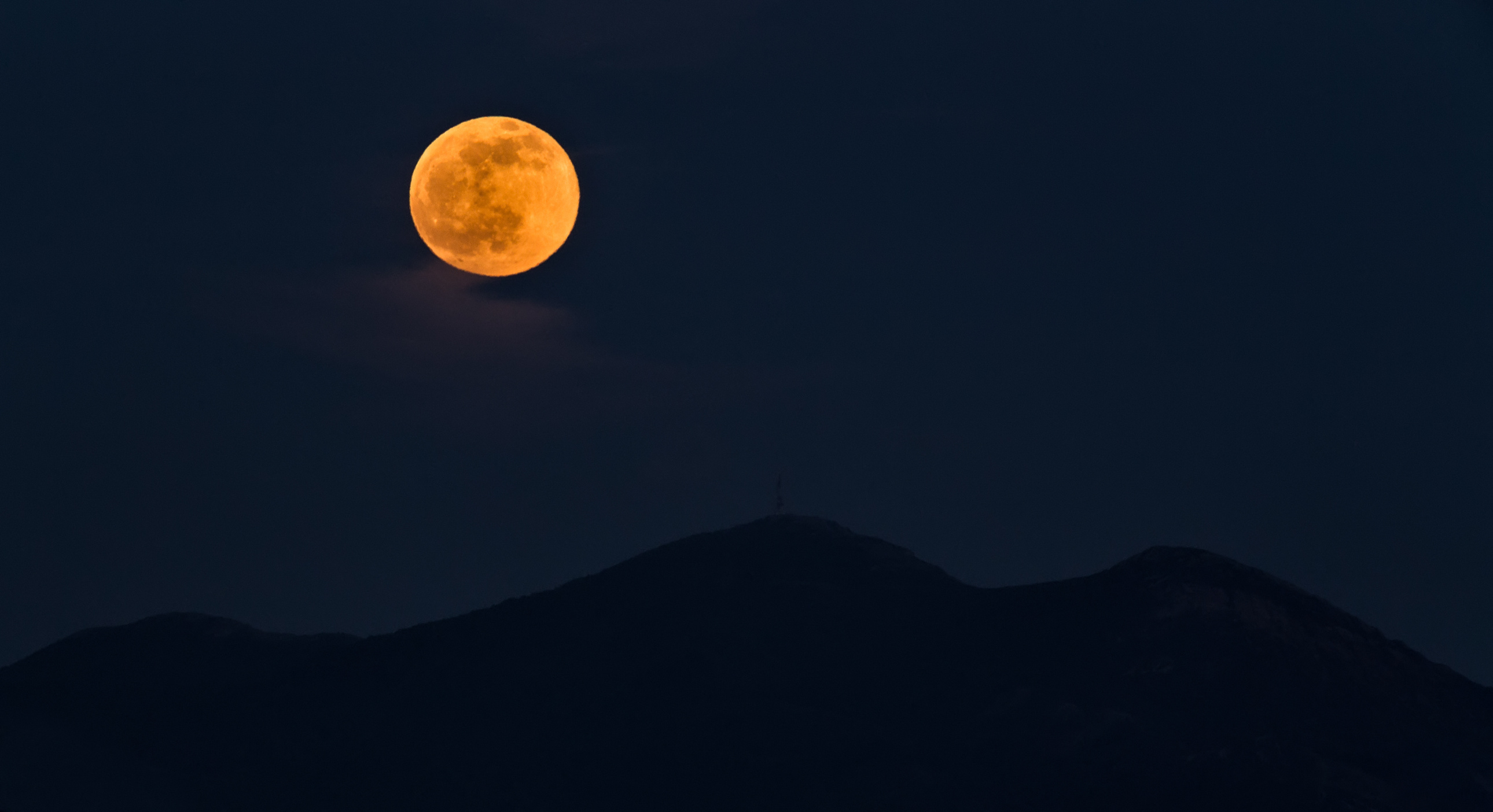 Full orange moon rising over the mountains